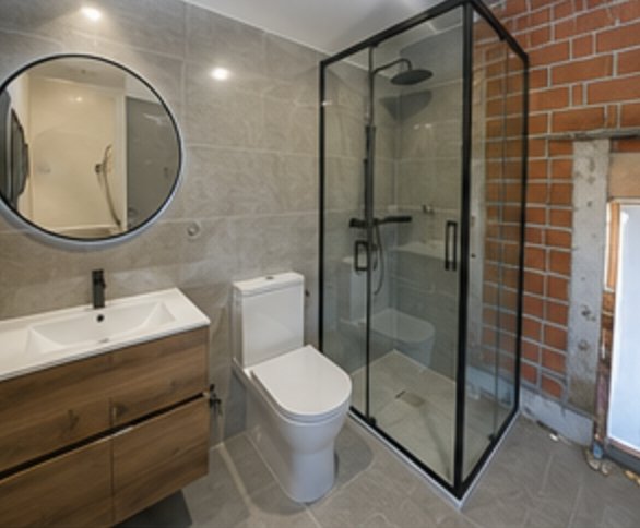 Baño reformado con ducha de obra y mueble de madera